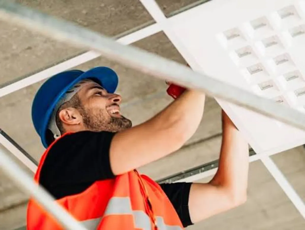 Técnico instalando iluminación para mantenimiento de inmuebles